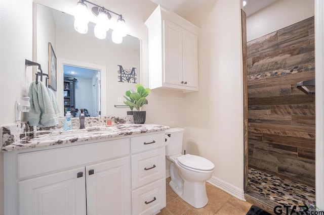 full bathroom with toilet, vanity, baseboards, tiled shower, and tile patterned floors