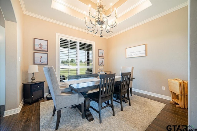 dining room featuring a chandelier, wood finished floors, baseboards, a raised ceiling, and crown molding