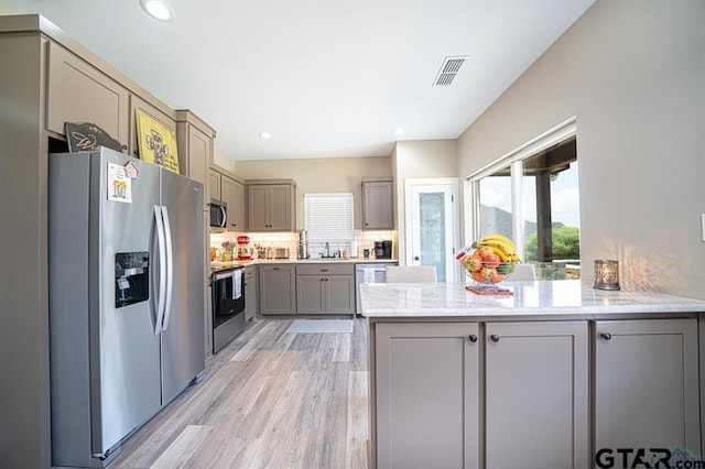 kitchen with visible vents, gray cabinetry, appliances with stainless steel finishes, a sink, and a peninsula