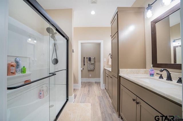 full bath featuring a stall shower, visible vents, baseboards, wood finished floors, and vanity