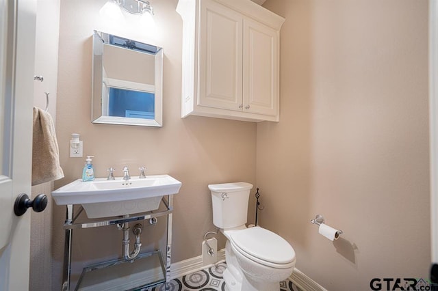 bathroom with toilet, baseboards, and a sink