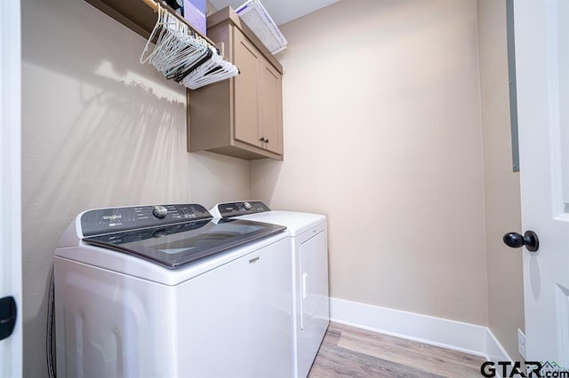 washroom featuring light wood finished floors, washing machine and clothes dryer, cabinet space, and baseboards