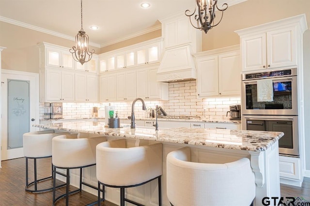 kitchen featuring stainless steel appliances, ornamental molding, dark wood finished floors, and an inviting chandelier