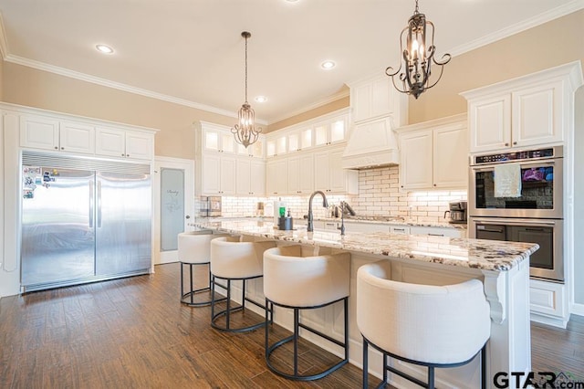 kitchen with an inviting chandelier, dark wood-style floors, stainless steel appliances, and a sink