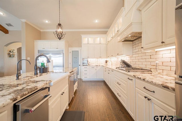 kitchen with premium range hood, dark wood-type flooring, appliances with stainless steel finishes, and light stone countertops