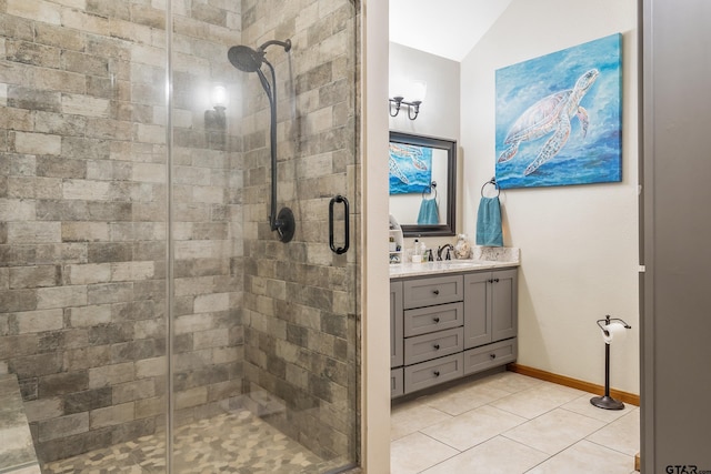 bathroom featuring a stall shower, baseboards, lofted ceiling, tile patterned floors, and vanity