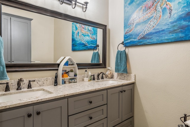 full bathroom with a textured wall, double vanity, and a sink