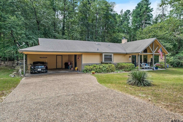 view of front of house featuring driveway, roof with shingles, a carport, a chimney, and a front yard