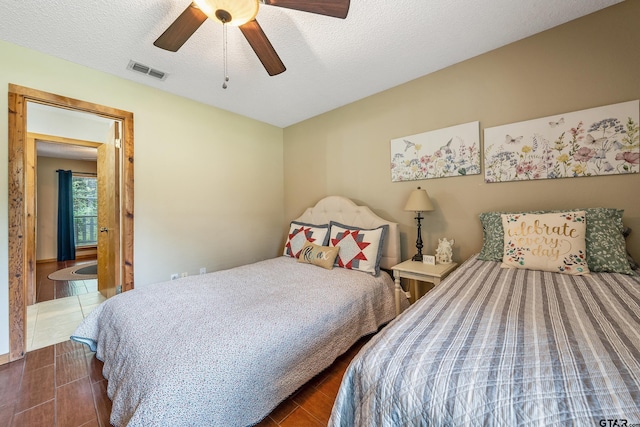 bedroom featuring visible vents, ceiling fan, a textured ceiling, and wood finished floors