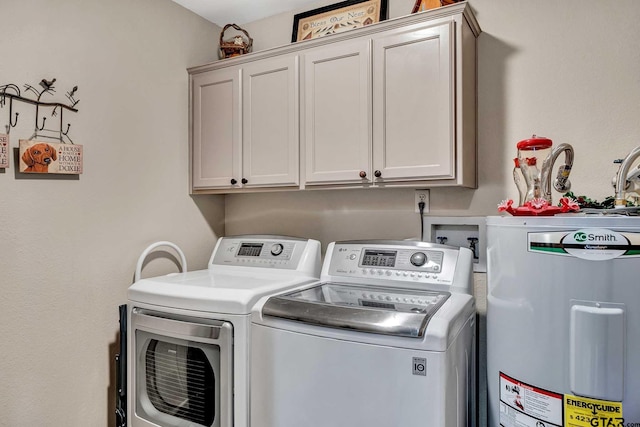 washroom featuring water heater, washing machine and clothes dryer, and cabinet space