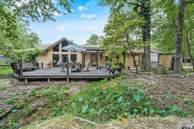 rear view of house featuring fence, a wooden deck, and a pergola