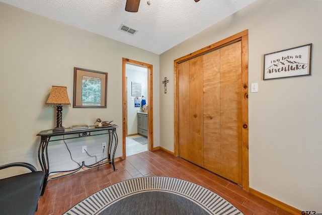 entrance foyer featuring a textured ceiling, baseboards, visible vents, and wood tiled floor