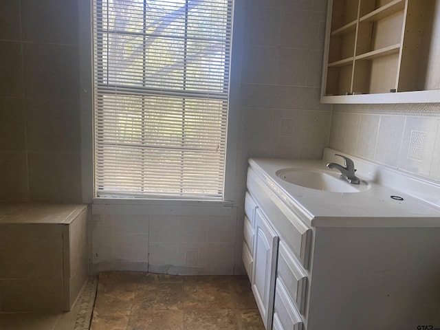 bathroom with vanity, a healthy amount of sunlight, and tile walls