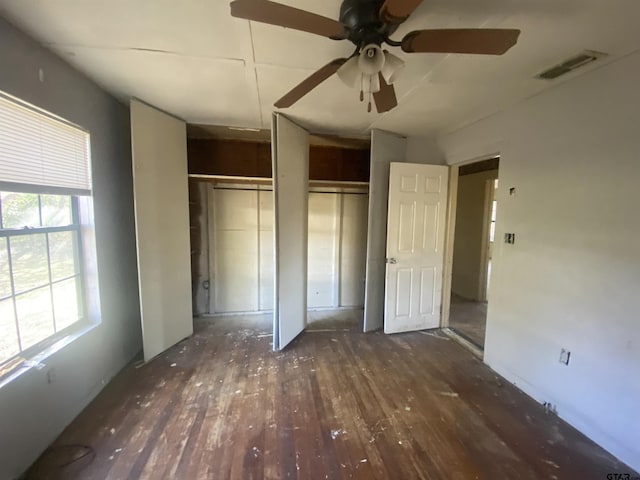 unfurnished bedroom featuring ceiling fan, dark hardwood / wood-style flooring, and two closets