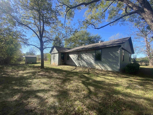 view of side of property with a yard and a shed