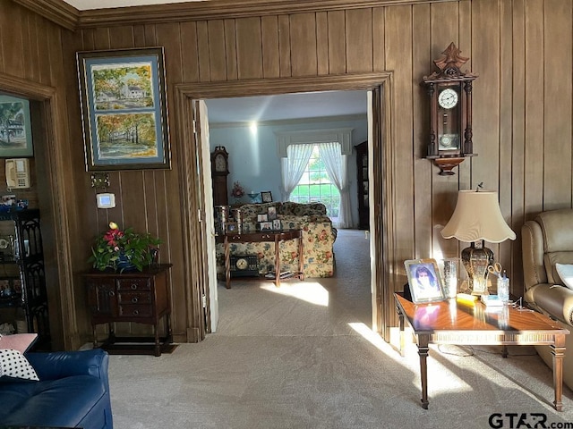 hallway featuring ornamental molding, carpet flooring, and wooden walls