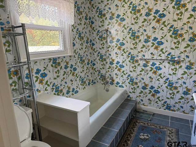 bathroom with tiled bath, tile patterned flooring, and toilet