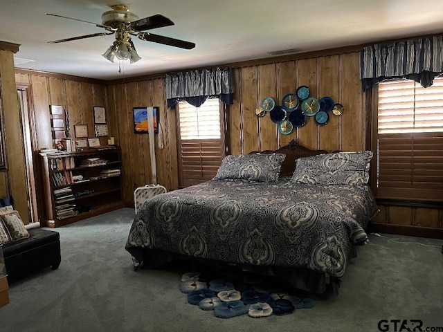 carpeted bedroom featuring wood walls, ceiling fan, and ornamental molding