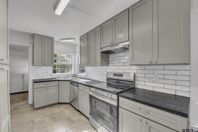 315 E Hubbard St, Lindale, TX 75771 - kitchen featuring stainless steel appliances, under cabinet range hood, backsplash, gray cabinetry, and a textured ceiling