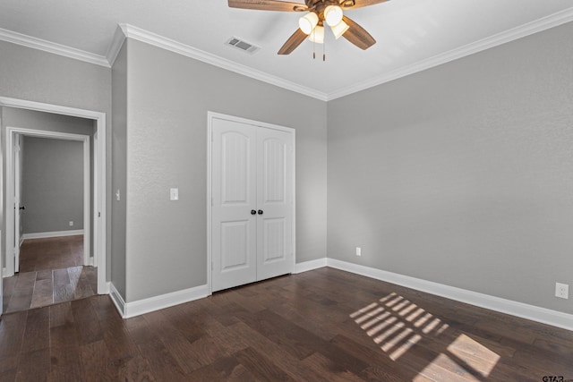 unfurnished bedroom featuring dark wood-type flooring, ceiling fan, crown molding, and a closet