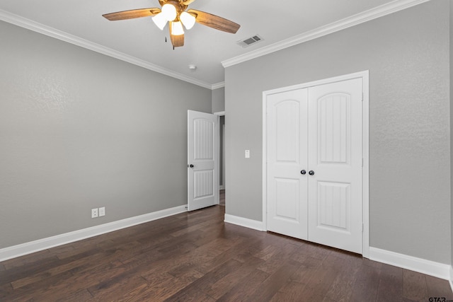 unfurnished bedroom featuring dark wood-type flooring, ceiling fan, a closet, and crown molding