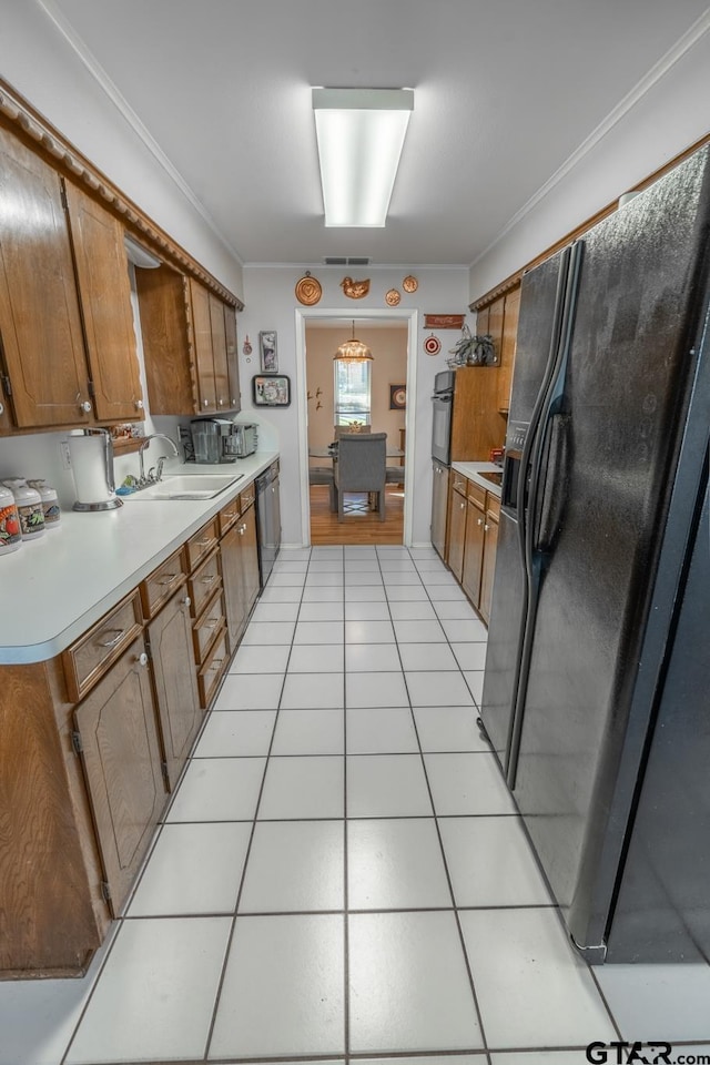 kitchen featuring pendant lighting, sink, crown molding, black appliances, and light tile patterned flooring