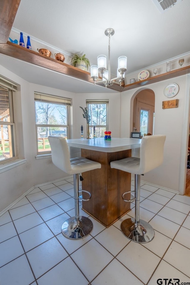 kitchen featuring light tile patterned floors, a kitchen breakfast bar, hanging light fixtures, and a healthy amount of sunlight