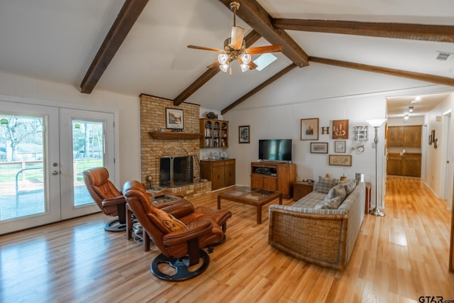 living room featuring wood-type flooring, vaulted ceiling with beams, ceiling fan, a brick fireplace, and french doors