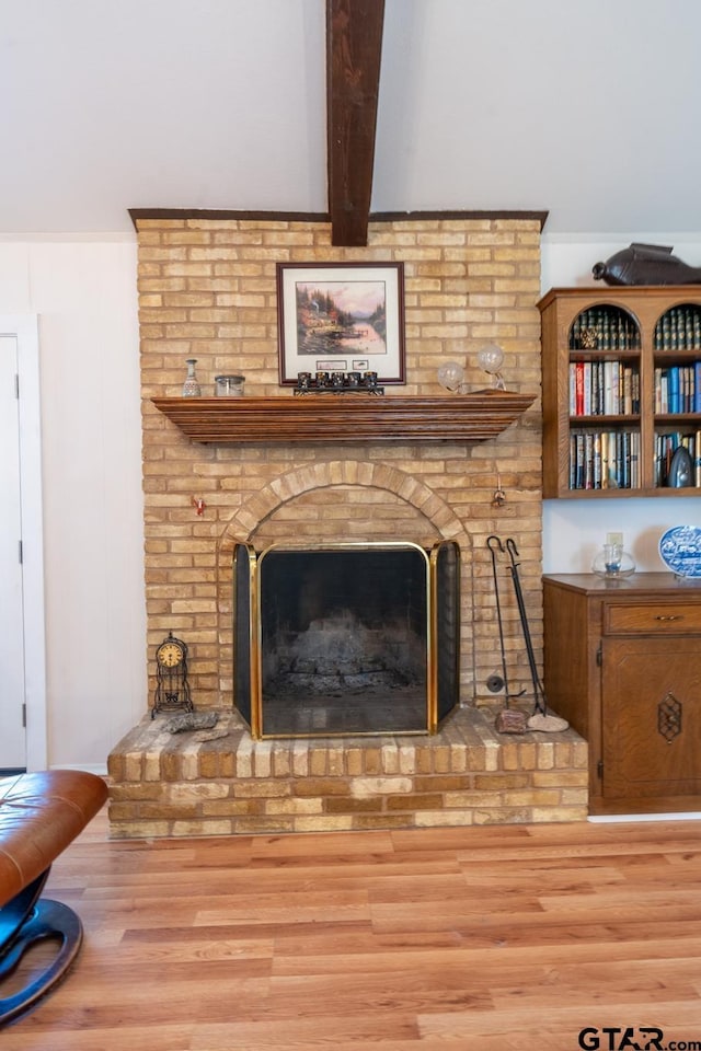 room details with beamed ceiling, wood-type flooring, ornamental molding, and a fireplace