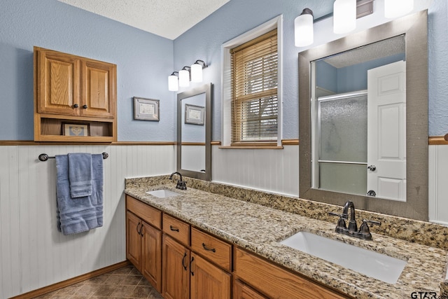 bathroom with vanity, tile patterned floors, a textured ceiling, and a shower with shower door