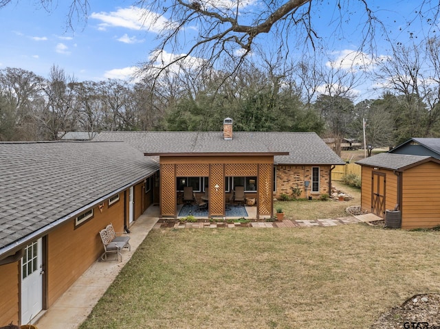 back of house with a lawn, a patio area, and a storage unit