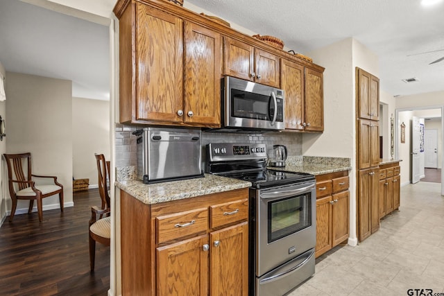 kitchen featuring stainless steel appliances, light stone counters, and decorative backsplash