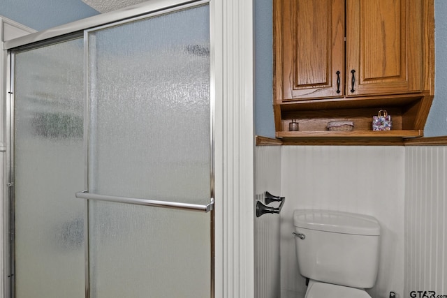 bathroom with a shower with shower door and toilet