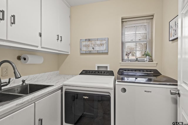 clothes washing area featuring cabinets, sink, and independent washer and dryer