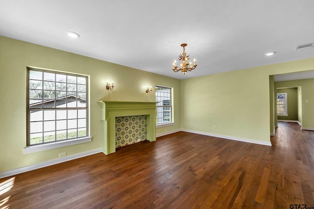 unfurnished living room with an inviting chandelier and dark hardwood / wood-style floors