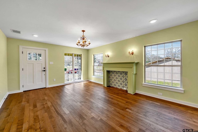 unfurnished living room featuring a notable chandelier, hardwood / wood-style flooring, and a healthy amount of sunlight