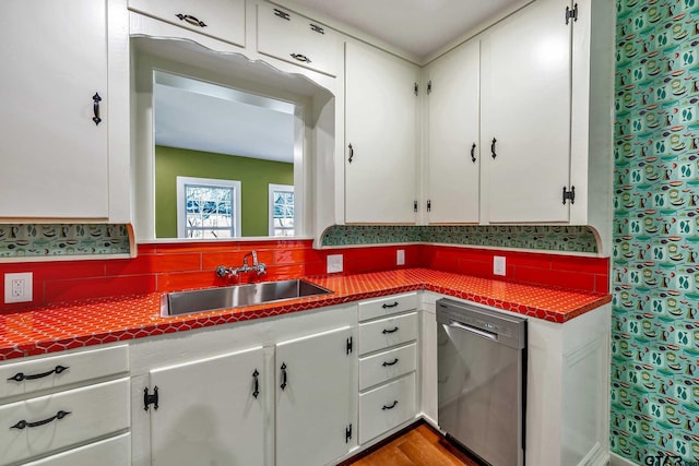 kitchen with white cabinetry, sink, backsplash, and stainless steel dishwasher