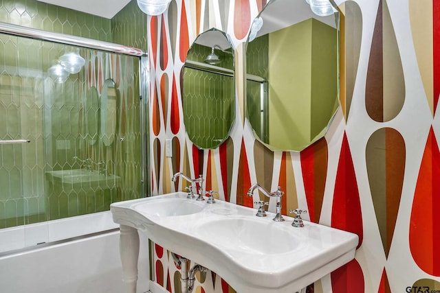 bathroom with bath / shower combo with glass door and dual sinks