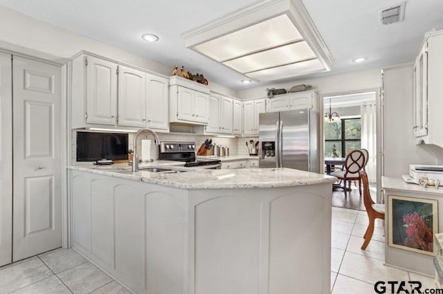 kitchen featuring light stone counters, appliances with stainless steel finishes, white cabinetry, a sink, and a peninsula