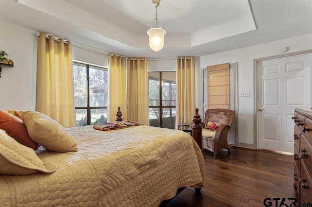 bedroom featuring a textured ceiling, a tray ceiling, and dark wood-type flooring