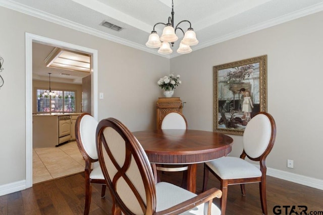 dining area featuring baseboards, visible vents, ornamental molding, wood finished floors, and a notable chandelier