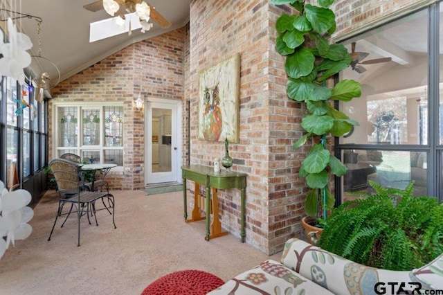 sunroom / solarium featuring lofted ceiling with skylight and ceiling fan