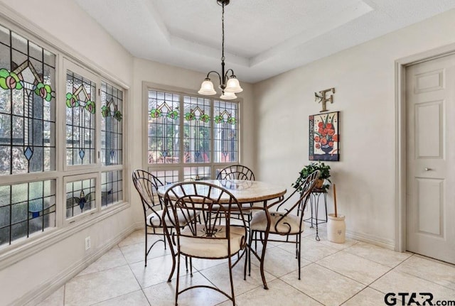 dining room with light tile patterned floors, baseboards, a raised ceiling, and an inviting chandelier