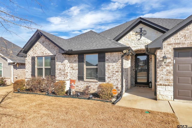 property entrance featuring a garage and a lawn