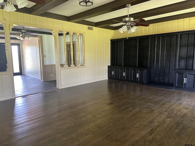 unfurnished living room featuring wood walls, dark hardwood / wood-style floors, and beam ceiling