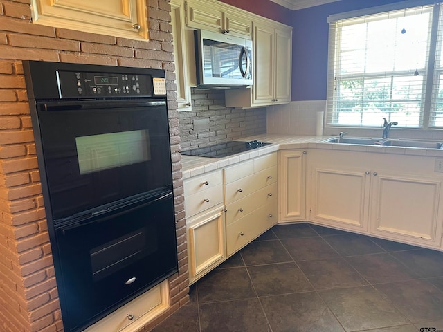 kitchen with tile counters, black appliances, sink, tasteful backsplash, and dark tile patterned floors