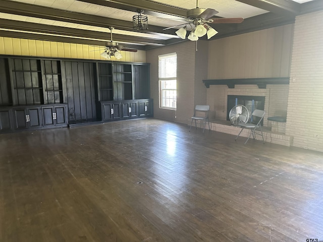 1248 Canada St, Jacksonville, TX 75766 - unfurnished living room with ceiling fan, a fireplace, beamed ceiling, brick wall, and wood finished floors