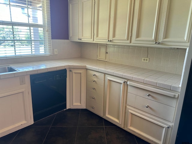 kitchen featuring dark tile patterned floors, backsplash, tile counters, and black dishwasher