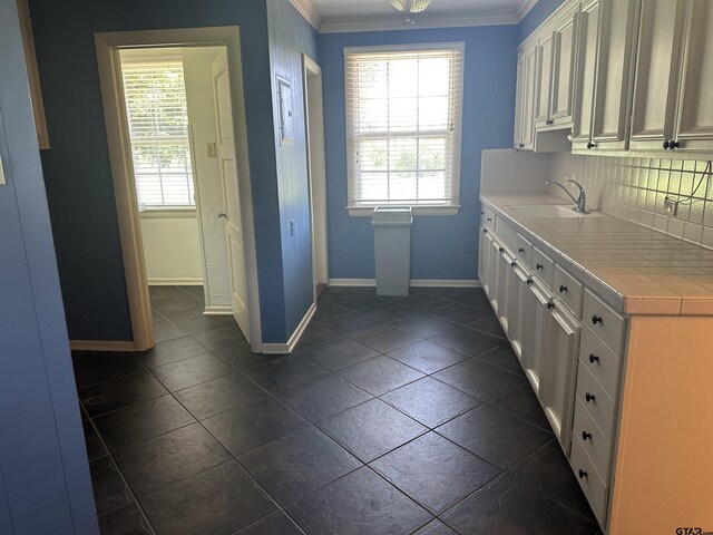1248 Canada St, Jacksonville, TX 75766 - kitchen with crown molding, a sink, baseboards, decorative backsplash, and dark tile patterned flooring