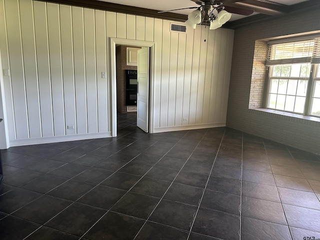 1248 Canada St, Jacksonville, TX 75766 - spare room with dark tile patterned flooring, ceiling fan, and wood walls